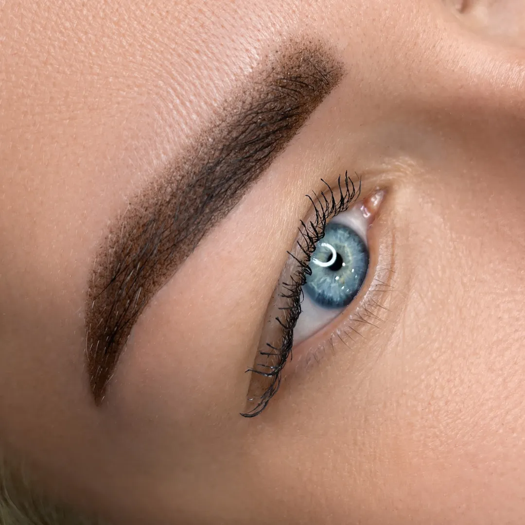 Close-up of a blue eye featuring powder brows, styled by Sweet Chanice for a soft, natural appearance.