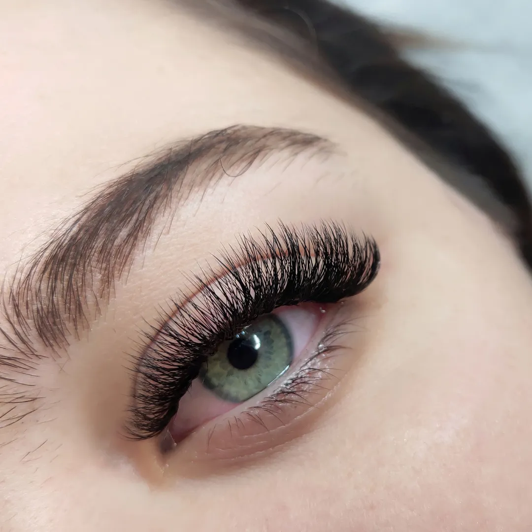 Green eye with fluffy lash extensions applied by Sweet Chanice for a voluminous, natural appearance.